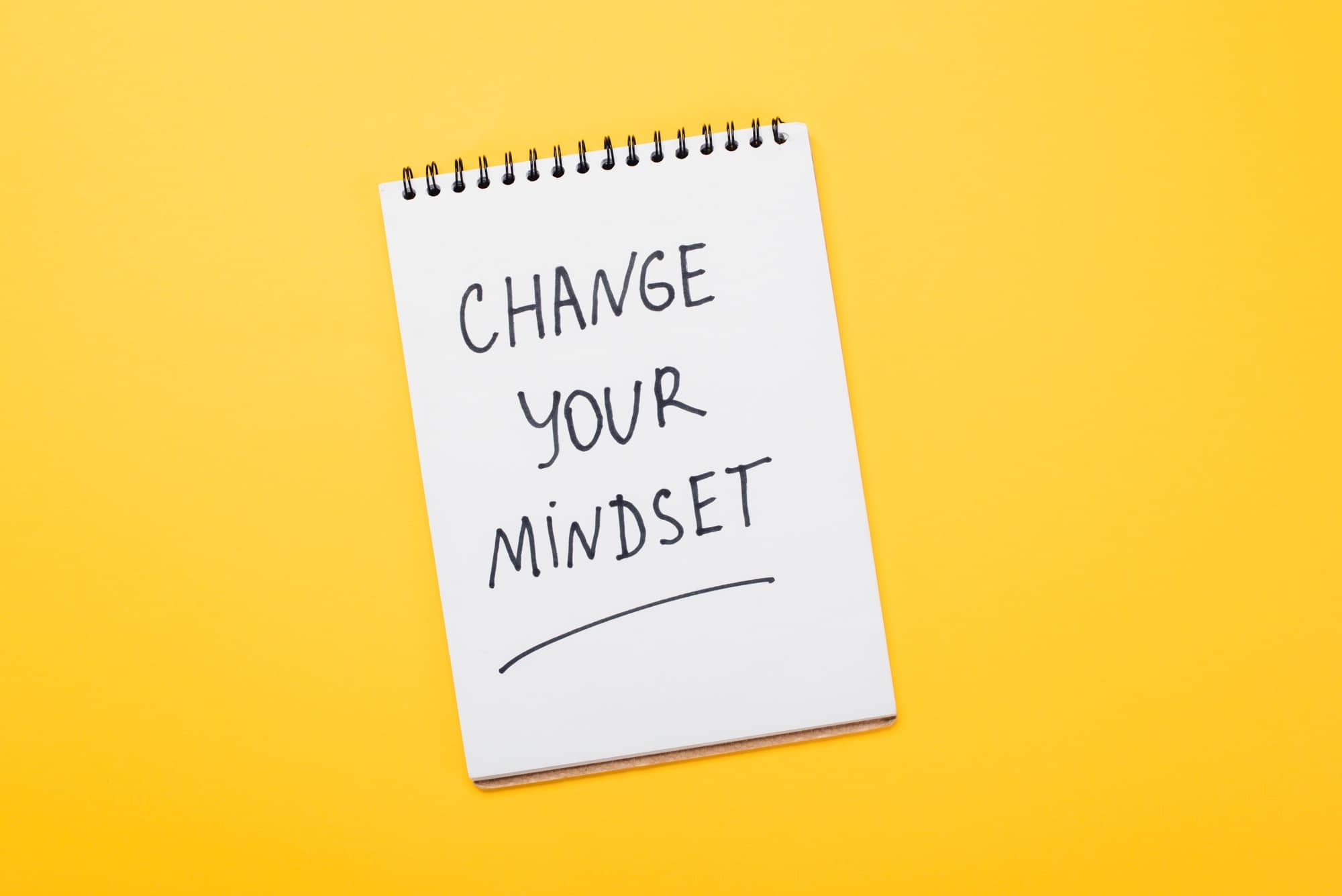 top view of notebook with change your mindset inscription on yellow surface