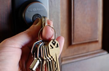 Woman unlocking deadbolt door lock with a set of keys